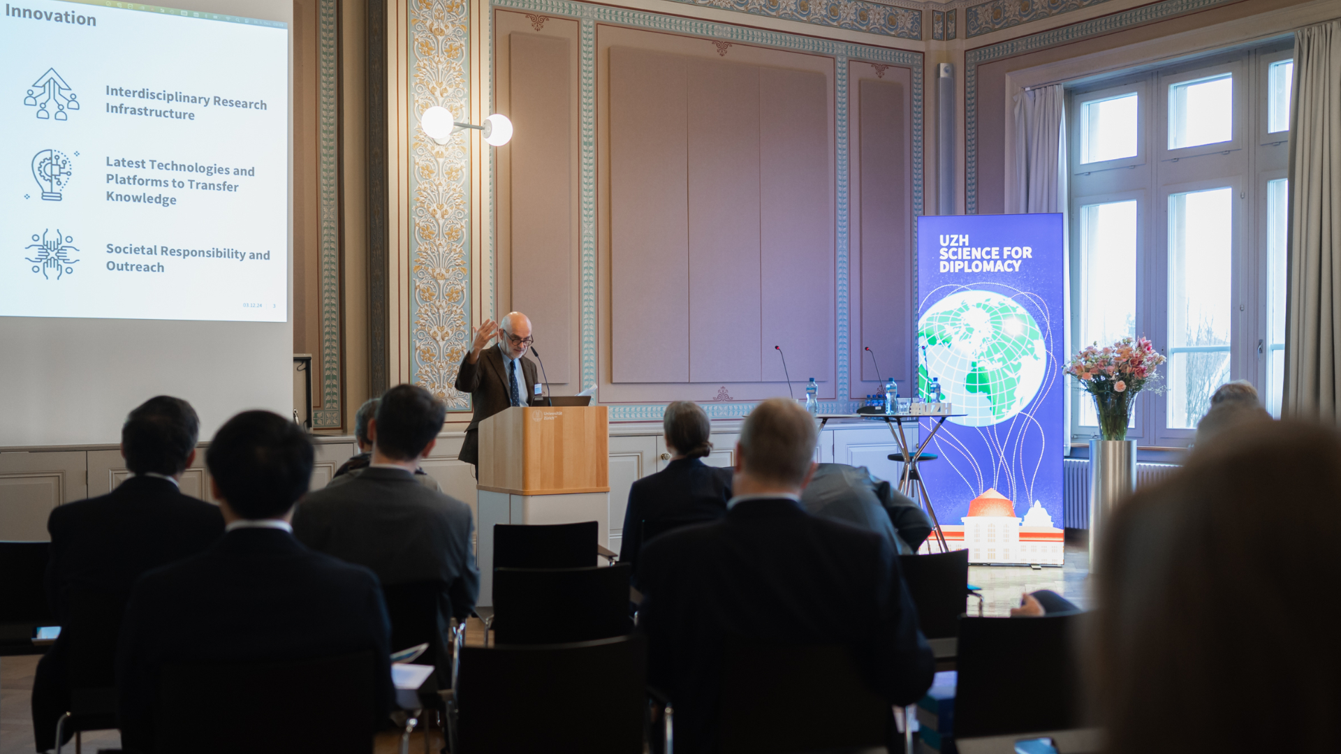 Prof. Francis Cheneval, UZH Professor of Political Philosophy, stands in front of an international audience of diplomatic representatives and introduces the event "UZH Science For Diplomacy". 